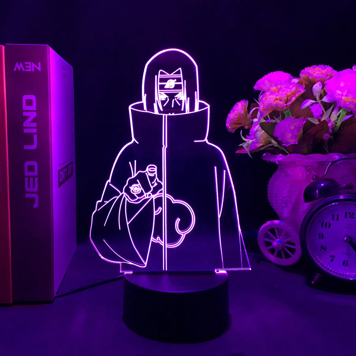 <img src="LED lamp featuring an outline illustration of Itachi Uchiha from Naruto and Naruto Shippuden during his time with the Akatsuki. He is depicted wearing the iconic Akatsuki cloak with a serious expression, pointing forward. The warm orange light highlights his headband and cloak, capturing his intense presence as a member of the Akatsuki.">